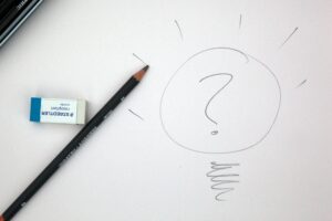 A white paper sheet with a drawing of a lamp bulb with a question mark in the it signifying an idea. There are also a pencil and a rubber on the sheet.
