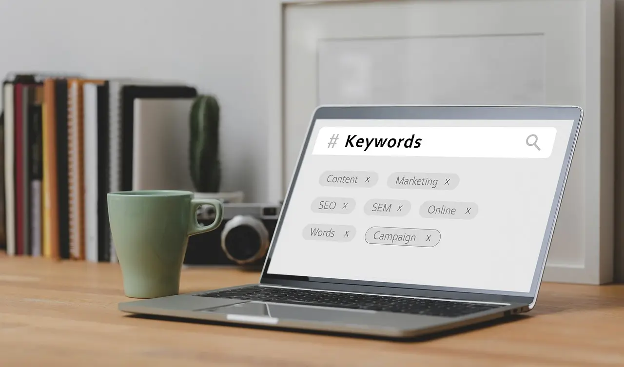 A laptop with the word "Keywords" and other elements of SEO written on its screen