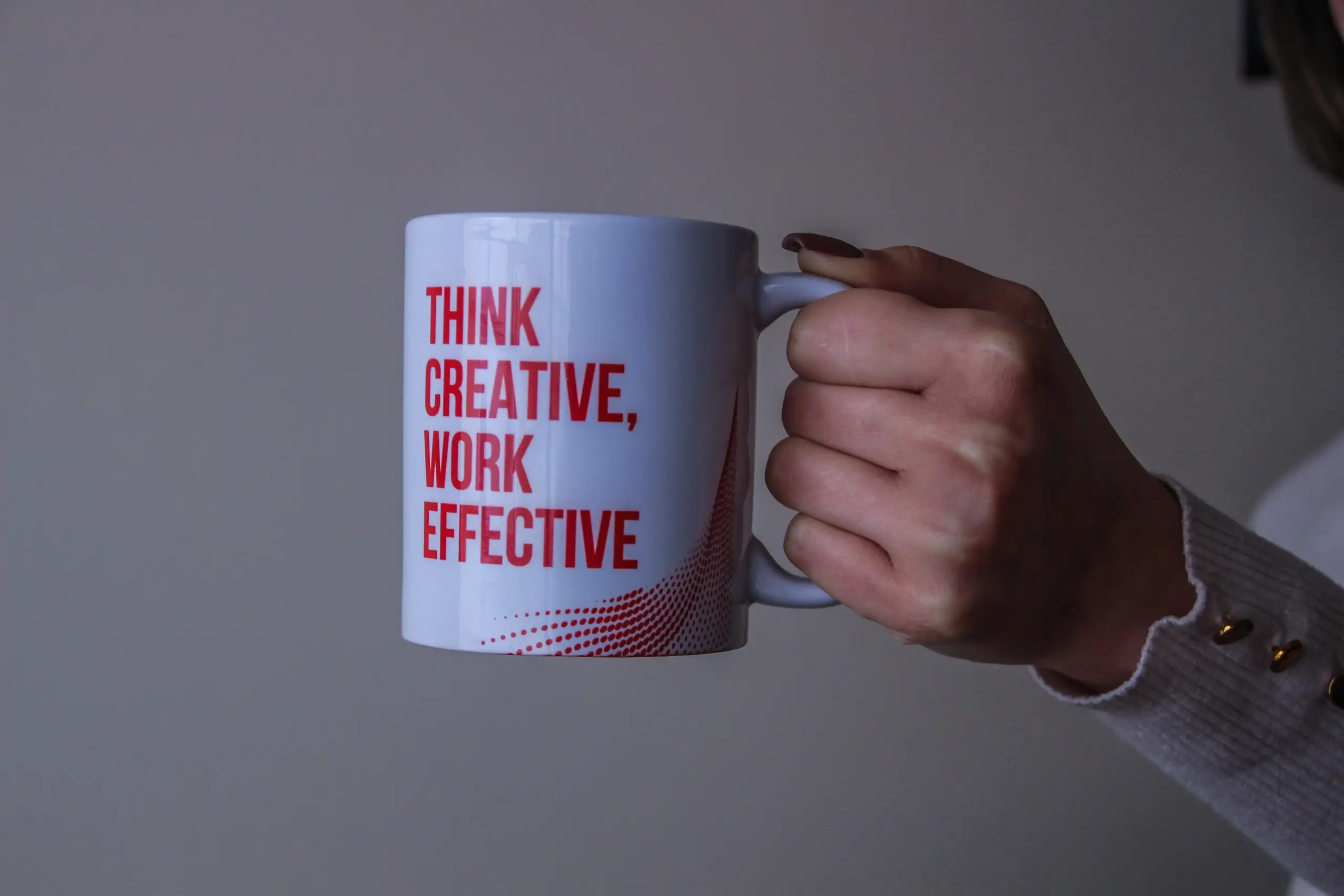 A hand holding a cup with a phrase "Think Effective, Work Effective" written on it