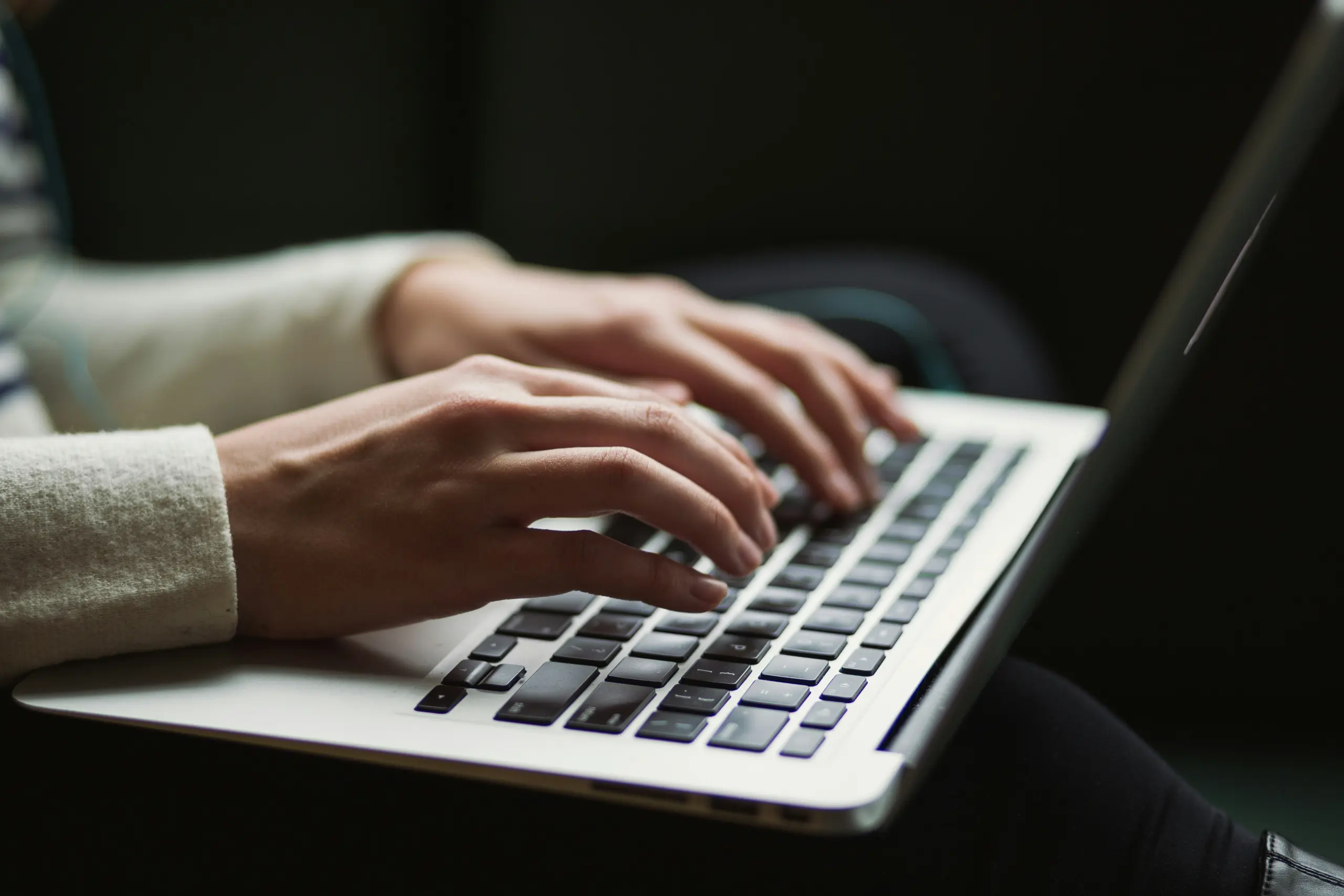 A woman's hands typing on a laptop's keyboard
