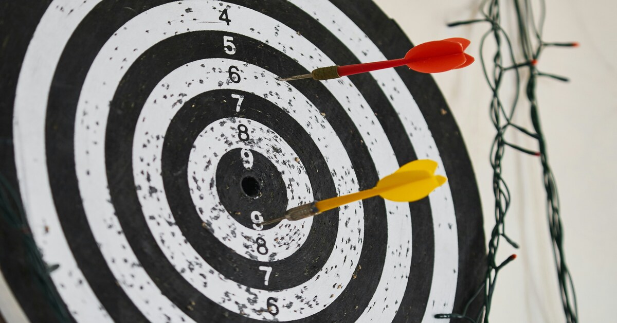 A dartboard with darts hitting near the bullseye represents the goal of effectively outsourcing content creation.