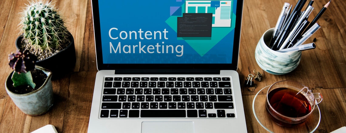 A laptop displaying the words “Content Marketing” on the screen, surrounded by workspace items, symbolizing content marketing success metrics.