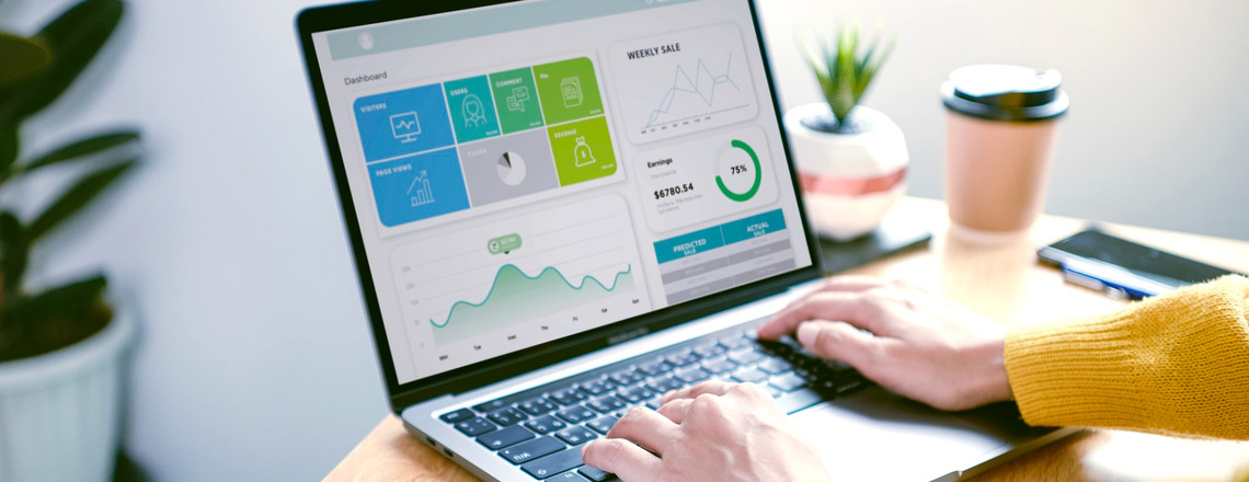 Hands typing on a laptop displaying a dashboard with graphs and data, focusing on content marketing success metrics.