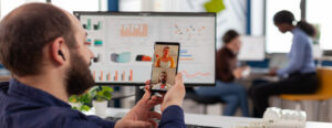 A professional participates in a video call on lead generation, with data analytics displayed on a computer screen in the background.